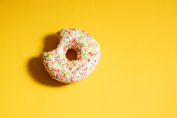 Yellow frosted donut with colorful sprinkles.