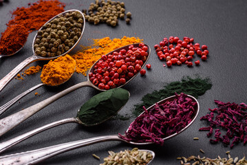 Several types of spices in metal spoons paprika, tomatoes, curry, beets, cumin, turmeric, fennel, spirulina