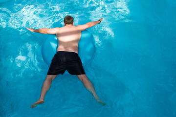 A man floats an inflatable circle, top view.