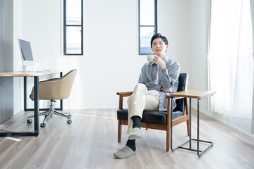 家でコーヒーを飲んでリラックスする若い男性