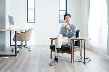 家でコーヒーを飲んでリラックスする若い男性