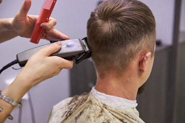 Fototapeta premium hairdresser cuts hair with a machine clipper. Haircut service. Man hairstyle