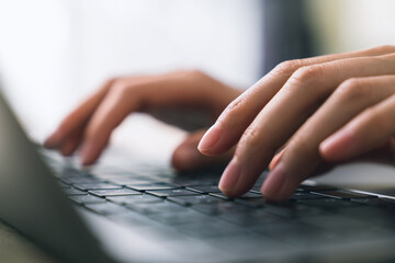 Hand using laptop and hand typing on the computer keyboard in the office.