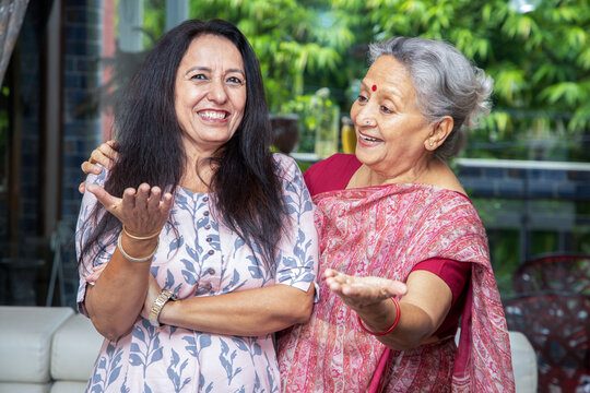 Cheerful Indian Mother And Daughter Laughing And Talking Together At Home.