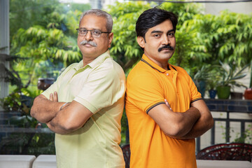 Portrait of indian senior father and son standing together looking at camera.