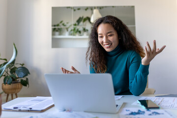 Asian businesswoman on a video call while sitting at her desk.Cropped shot of an attractive young woman using her laptop to make a video call at home