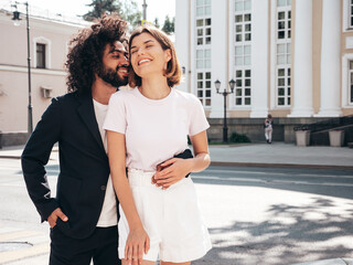 Fototapeta premium Smiling beautiful woman and her handsome boyfriend. Sexy cheerful multiracial family having tender moments in the street at sunset. Multiethnic models hugging. Embracing each other. Love concept