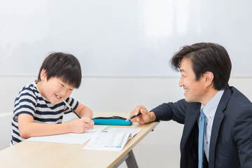 小学生に授業で勉強・漢字を教える笑顔の個別指導の塾講師・先生（日本人男性）
