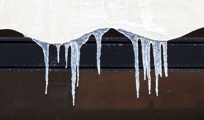 Icicles hang on a house roof, close up photo with selective soft focus