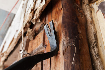 Steel nail puller removes a nail out of a wall - obrazy, fototapety, plakaty