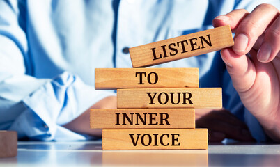 Closeup on businessman holding a wooden block with "listen to your inner voice"