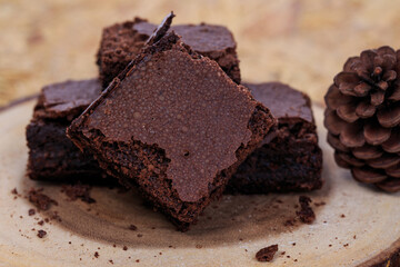 Pieces of fresh chocolate brownie on wooden plate on white background. Stack of fudgy chocolate...