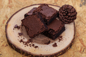 Pieces of fresh chocolate brownie on wooden plate on white background. Stack of fudgy chocolate brownies on white background, homemade bakery and dessert.