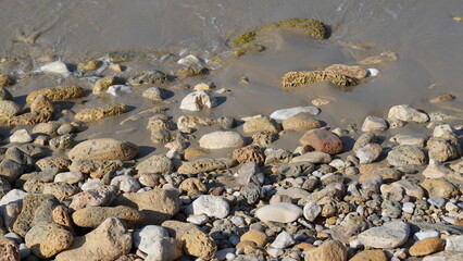 Cobble pieces of marble rock near water edge in Caesarea Maritima National Park, Israel.