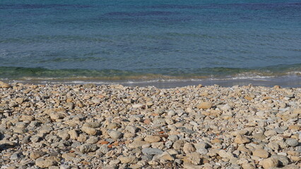 Cobble pieces of marble rock near water edge in Caesarea Maritima National Park, Israel.