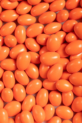 Chocolate dragee in the form of a pile. Orange dragee chocolate with chocolate filling. Top view. close up