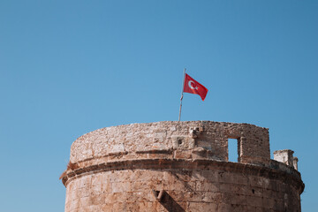 Stone Fortress and Turkish flag in the old town of Kaleici. Hidirlik Tower in Antalya, Turkey.