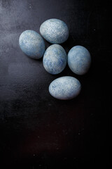 Easter eggs painted blue on black wooden background. Top view, copy space, vertical shot