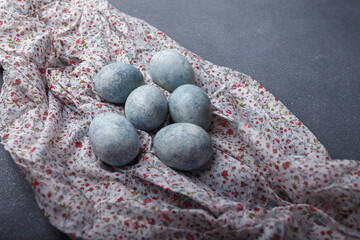 Easter eggs DIY painted blue on grey wooden background with kitchen towel. Copy space