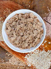 Ancient grain cereal flakes on rustic surface with grains 