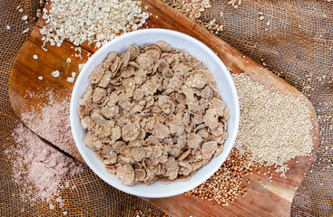 Ancient grain cereal flakes on rustic surface with grains 