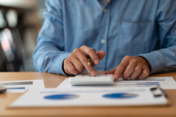 Hand of a business man using a calculator to check financial accounts, check expenditures and company budget. Female accountant calculating while working analyzing business reports at work