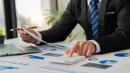 Hand of a business man using a calculator to check financial accounts, check expenditures and company budget. Female accountant calculating while working analyzing business reports at work