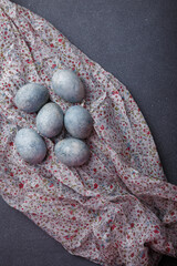Easter eggs DIY painted blue on grey wooden background with kitchen towel. Top view, copy space, vertical shot