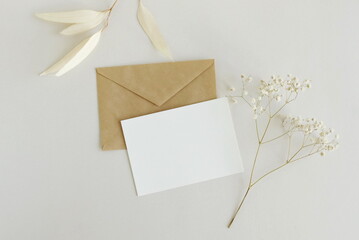 Greeting card mockup, envelope and  dried  flowers twigs on white background top view flatlay. Card...