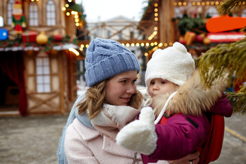 Obraz premium Mother and daughter are walking around the city on Christmas and New Year holidays. Portrait of happy mother and daughter having fun in the street