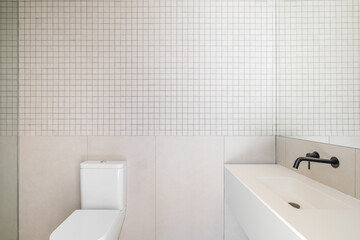 Fototapeta na wymiar Modern minimalist bathroom interior design with white sink, toilet, beige tiles, and large mirror.