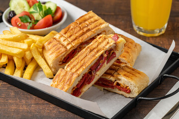 Toast with cheddar cheese and turkish sausage with french fries and salad on wooden table