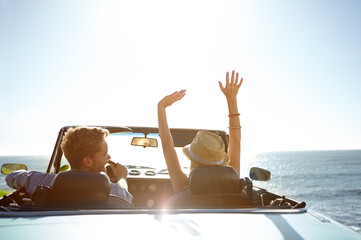 Car, road trip and travel with a couple by the beach on a drive to enjoy the view during summer together. Freedom, transport and driver with a woman sitting hands raised by the ocean with her man