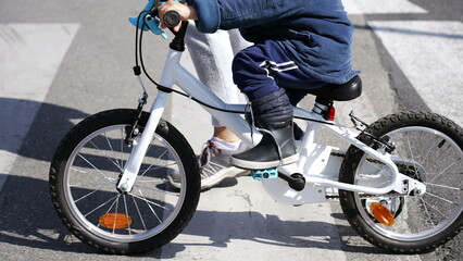 Obraz premium Child cyclist crossing street with mother on zebra lines crosswalk. Little kid riding bicycle outdoors