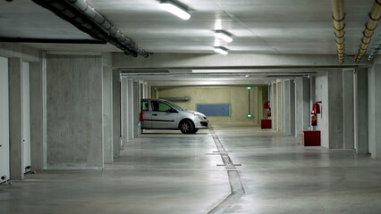 Car exiting underground building parking space in white grey vehicle. Garage modern interior