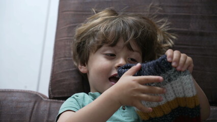 Fototapeta premium One child putting beanie indoors. Cute small boy wearing knit wool winter accessory
