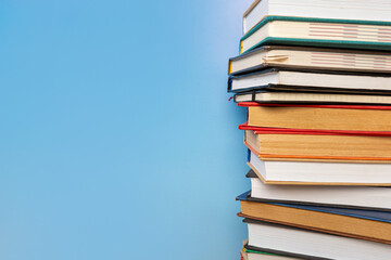 Stack of books in the colored cover lay on blue backround. Education learning concept