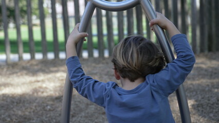 Child spinning at playground spinner structure. One little boy having fun at play space with stainless steel toy