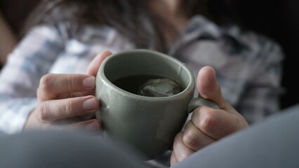 Woman holding cup of tea mug. Female hand closeup holds hot beverage