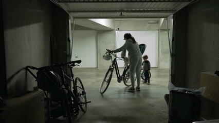 Person opening parking garage door and taking bicycle for a ride. Mother sliding metal gate at...