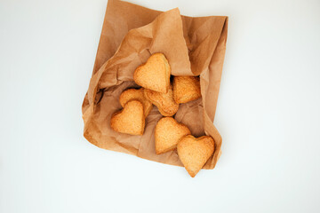 Shortbread cookies in the form of hearts in a brown paper bag on a white table. Top view