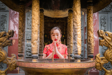 Portrait Asian Chinese girl wearing dress traditional Cheongsam suit pay respect for lucky life with chinese god temple is chinese festival concept.