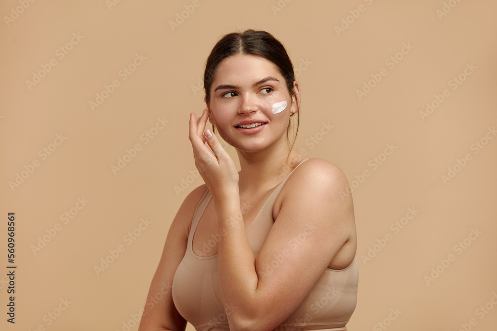 Wall mural Positive Woman Applying Face Cream. Closeup Of Female Model With Fresh Skin Applying Cosmetic Product Under Eyes. Skincare Concept. High Resolution 