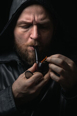 Portrait of a Bearded man in Black Rain Jacket Smoking a Pipe
