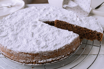 Juicy chocolate almond cake on a cooling rack. Traditional italian torta caprese on white background