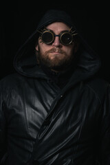 A man in a hood, wearing vintage steampunk goggles looking at the camera close-up