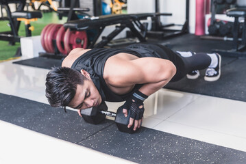 Fototapeta na wymiar A handsome asian man does close grip pushups off of a single hex dumbbell. Chest, anterior deltoid and tricep training.