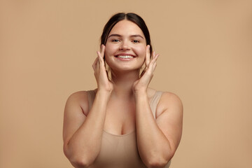 Obraz premium Smiling Woman Touching Face. Waist up Portrait of Attractive Woman Touching her Skin and Smiling While Applying Moisturiser. Woman Appearance and Skin Care Concept 