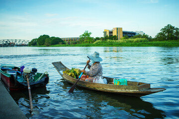 female merchant paddle a boat sell fruits on the river