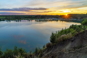 Fototapeta na wymiar Sunset over the horizon and at the water quarry . Leningrad region. Vsevolozhsk.